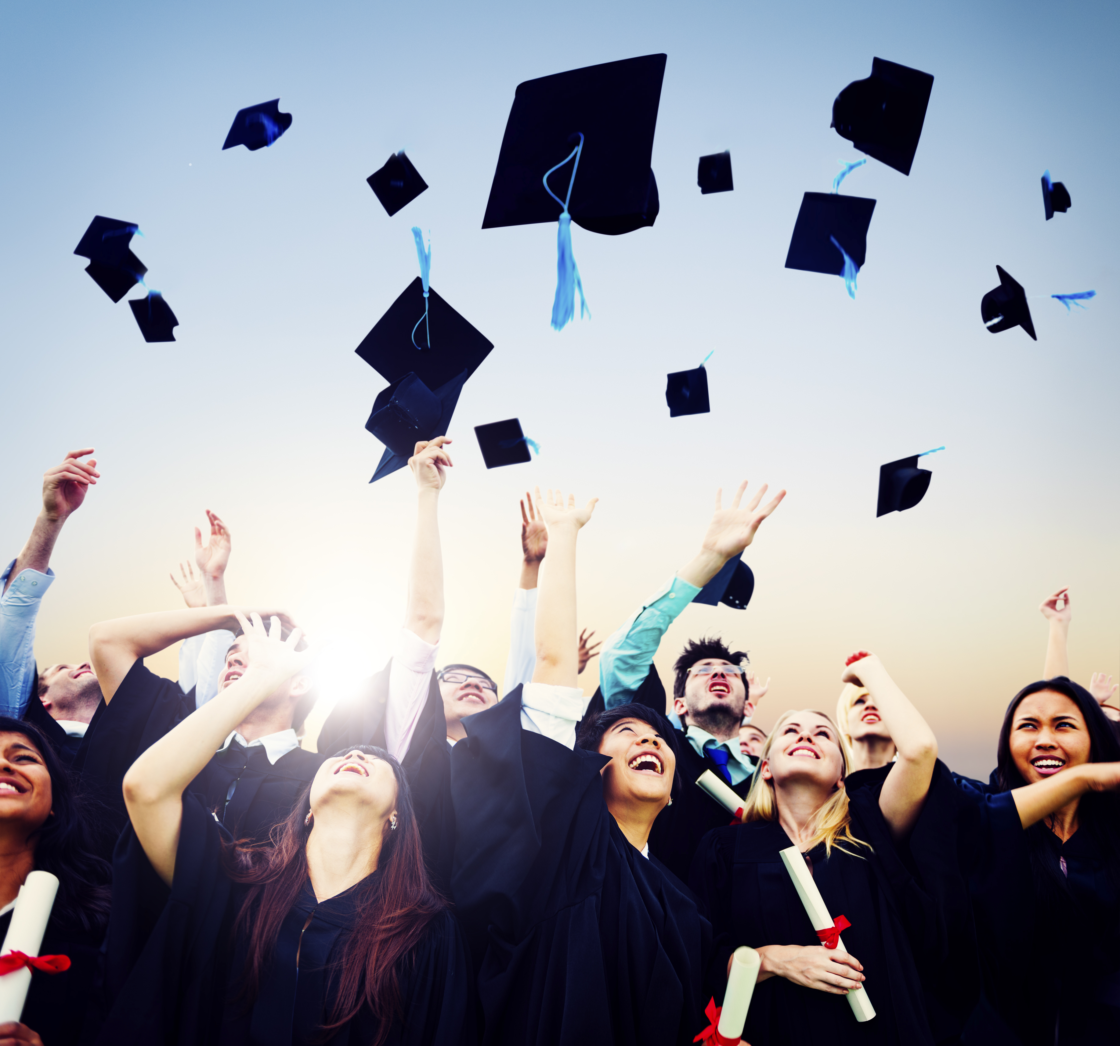 Cheerful students throwing graduation caps in the Air